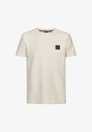 Cremefarbenes T-Shirt mit rundem Ausschnitt, kurzen Ärmeln und einem texturierten Stoff sowie einem kleinen schwarzen Aufnäher auf der linken Brust.