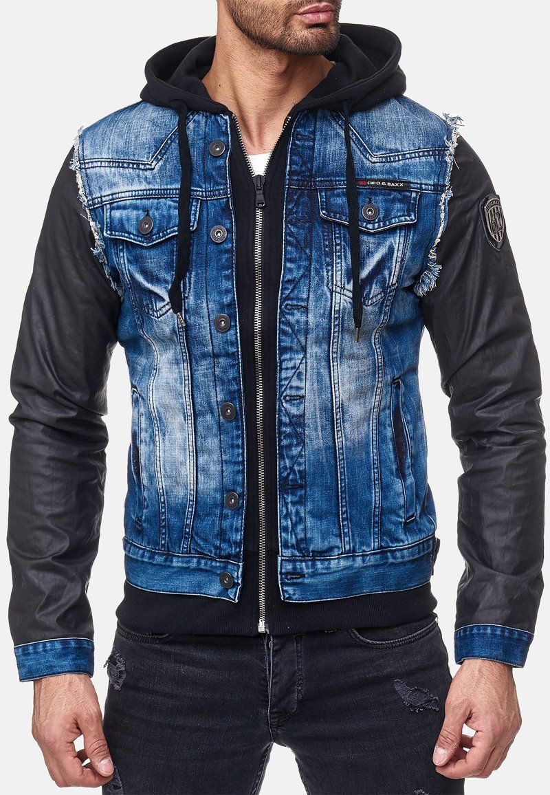 Giacca di denim con un frontale blu sbiadito, maniche in pelle nera e cappuccio, dotata di due tasche sul petto e dettagli consumati.