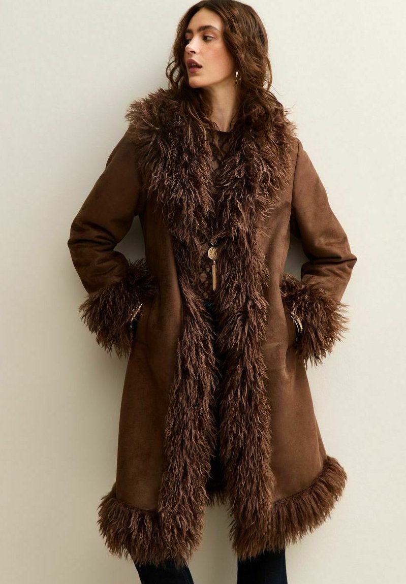 Bruine faux suede jas met een dikke, textuurvolle bontkraag en manchetten. Beschikt over een volledige voorkantopening en een relaxte pasvorm voor comfort.