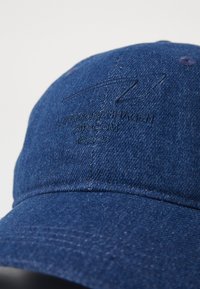 Dunkelblaue Denim-Mütze mit gesticktem Logo auf der Vorderseite. Leicht gebogener Schirm und strukturierter Stoff für einen lässigen Look.