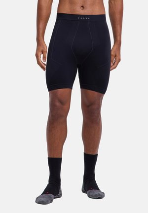 Modello maschile che indossa pantaloncini compressivi sportivi aderenti neri e calzini alla caviglia neri con dita grigie, mostrato dalla vita ai piedi.