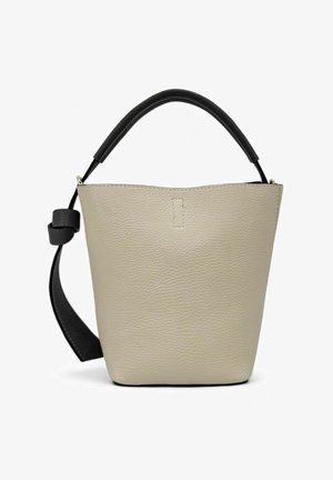 Sac seau en cuir beige texturé avec une poignée supérieure noire et une bandoulière réglable. Il présente un design minimaliste et une fermeture ouverte.