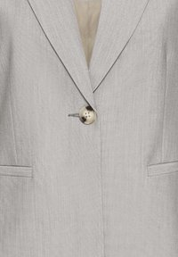 Svetlo sivi blazer s teksturirano tkanino, en gumb za zapiranje, dvema sprednjima žepoma in režastimi ovratniki. Vidna je gladka notranja podloga.