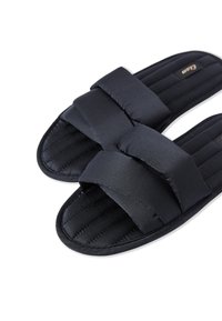 Pantofole nere imbottite con due fasce sovrapposte, texture cucita e suola piatta. Il materiale morbido offre comfort per l'uso interno.