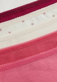 En uppsättning av fyra tygbitar i olika nyanser av rosa och rött, med spetskant och prickmönster på en av bitarna.
