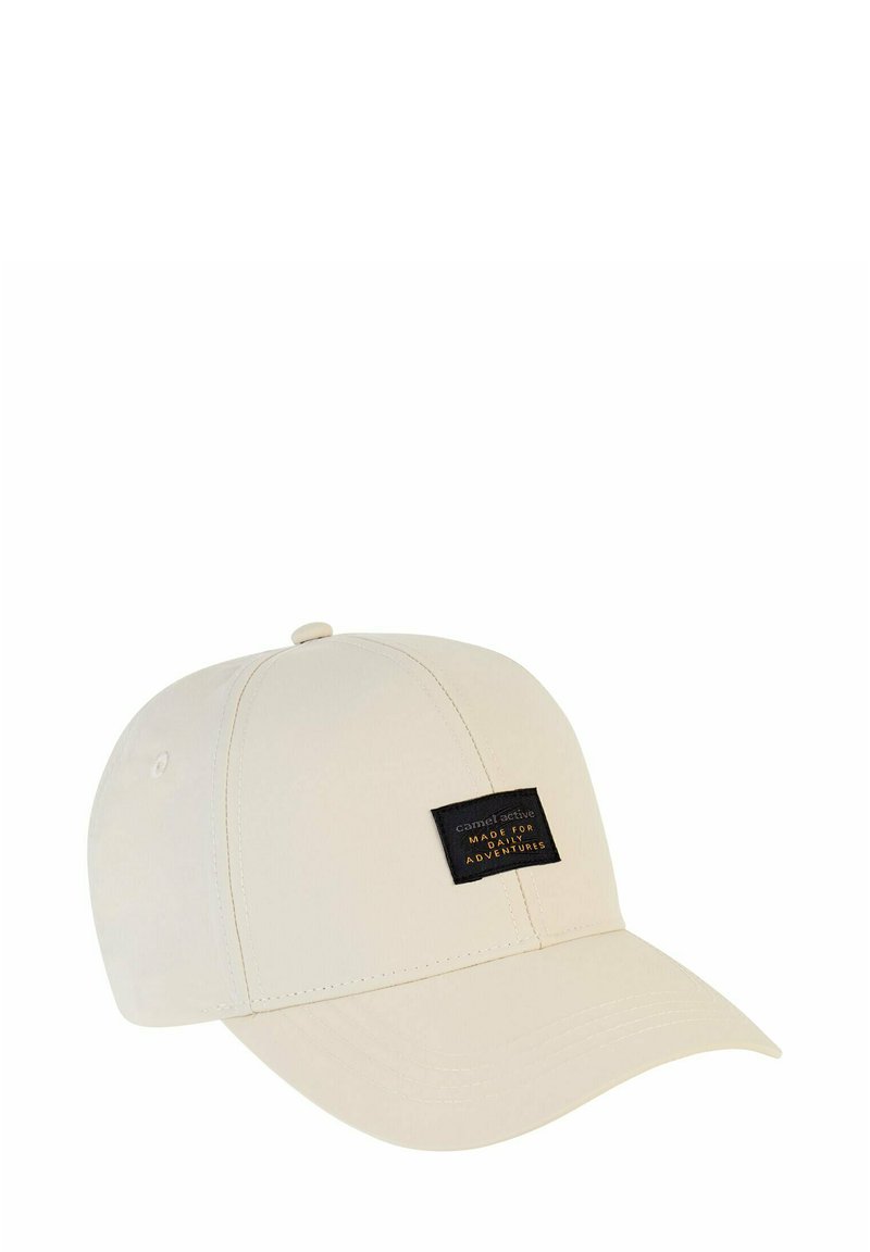 Beżowa czapka z zakrzywionym daszkiem, wykonana z miękkiego materiału. Posiada czarną metkę z białym napisem z przodu.