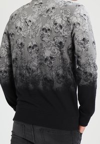 Maglione con sfumatura dal grigio al nero, decorato sul retro e sulle maniche da un dettagliato motivo di teschi neri e rose.