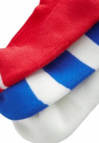 Punaiset, siniset ja valkoiset sukat pinottuina. Punaisessa sukan on uritettua pintaa, kun taas sinisessä sukassa on vaakasuoria valkoisia raitoja, ja valkoinen sukka on tasainen.