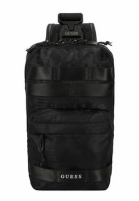 Zaino in nylon nero con superficie testurizzata, tasca frontale con zip e spallacci regolabili. Presenta il logo "GUESS" e webbing in stile tattico.