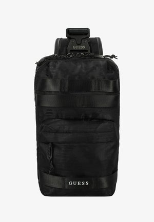 Schwarzer Nylon-Rucksack mit strukturierter Oberfläche, vorderer Reißverschluss-Tasche und verstellbarem Tragegurt. Mit "GUESS"-Logo und taktischem Gurtband.