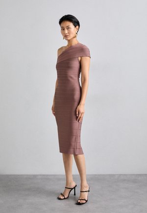 Taliowana sukienka na jedno ramię w mauve z prążkowanej tkaniny, do kolan, w poziome paski. Nosi ją z czarnymi sandałkami na obcasie.