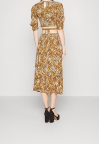 Leopardenmuster Midi-Kleid mit einem taillierten Crop-Top und Puffärmeln. Riemen im Rücken mit einem Schlüssellochauschnitt. Kombiniert mit schwarzen Blockabsatzschuhen.