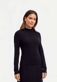 Maglione nero aderente con texture a coste, collo alto e maniche lunghe; realizzato in materiale elasticizzato. Design senza cuciture e senza decorazioni.