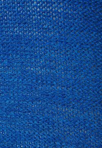 Närbild av blått stickat nätväv med detaljerad strukturerad garntextur bestående av öglor och sammanflätade trådar.