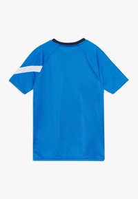 Camisa deportiva de manga corta azul con una franja blanca en la manga izquierda y un ribete negro en el cuello, vista desde la parte de atrás.