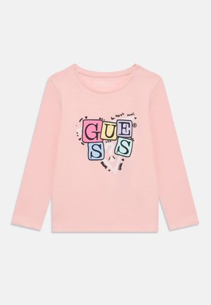 Růžová košile s dlouhým rukávem, která se pyšní barevným grafickým designem se slovem "GUESS" a hravými detaily, vyrobená z měkké bavlny.
