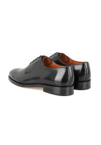 Chaussures habillées en cuir noir avec une finition lisse, bout arrondi et coutures minimales. Semelle noire épaisse avec un léger talon. Doublure intérieure marron.