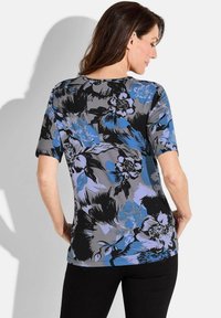 Blumen-T-Shirt mit grauem Hintergrund und blauen sowie schwarzen abstrakten Blumen, kurzen Ärmeln und rundem Halsausschnitt.