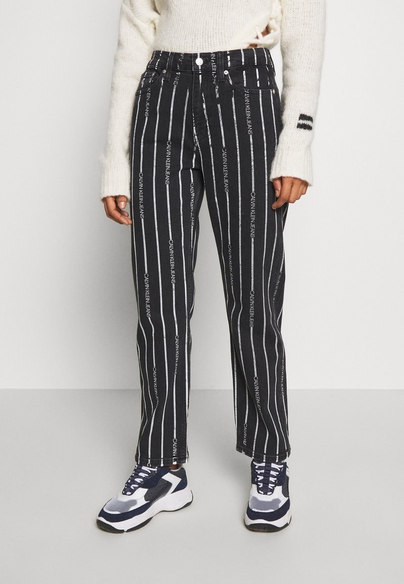 Svart och vitrandiga denimbyxor med tryckt "Calvin Klein Jeans"-logotyp. Rakt snitt med medelhög midja och metallknapp.