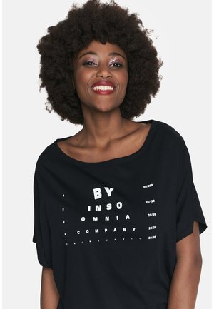 Czarna koszulka z bawełny o luźnym kroju. Zawiera biały nadruk przypominający tablicę do badania wzroku z napisami "BY INSOMNIA COMPANY" i cyframi.
