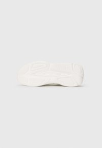 Hvit sneakersåle med teksturerte grep mønstre og merket "HUGO" preget nær hælen.