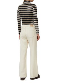 Pasiasty czarno-beżowy golf zestawiony z szerokimi, kremowobiałymi dżinsami. Charakterystycznym elementem jest skórzana naszywka na pasku dżinsów.