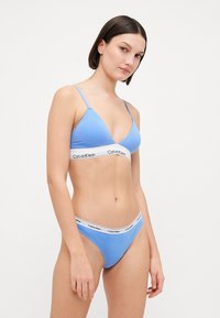 Svijetloplavi pamučni grudnjak i tangice s bijelom trakom na kojoj je logo "Calvin Klein". Mekana tekstura, trokutasti dizajn košarica, minimalni hardver.