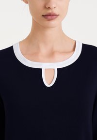 Top blu navy con colletto bianco e dettaglio a oblò all' neckline. Tessuto morbido con un design classico e semplice.