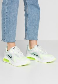 Las zapatillas Nike Air Max cuentan con una parte superior de malla blanca y verde claro, acentos negros y una unidad de aire neón verde visible.