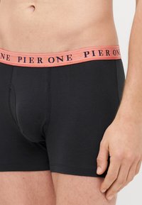 Fekete pamut boxer alsónadrág, kontrasztos barack színű derékpánttal, amelyen a "PIER ONE" kék betűkkel szerepel. Simaság, testhezálló kialakítás.