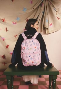 Rózsaszín hátizsák állatok és alakok illusztrált mintáival, két vállpánttal és elülső cipzáras zsebbel.