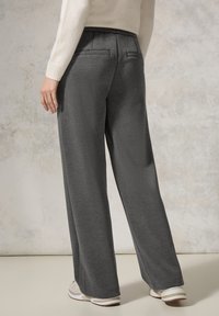 Pantalons gris à jambe large en tissu doux, présentant une coupe décontractée, une taille élastique et deux poches arrière.