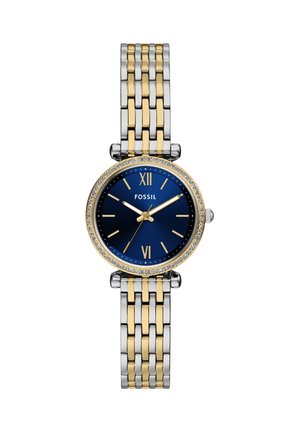 Rund Fossil armbåndsur med blå urskive, guld- og sølvledet rem, guld timeindikatorer og en krystalbesat bezel.