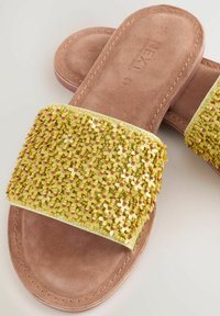 Lamedega, millel on kollane helmestega ülaosa, lilledega kaunistused ja heledast pruunist suede'ist tald. Pehme tekstuur ja libisev disain.