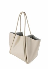 Beige nahkakäsilaukku, jossa on säädettävät kahvat, sileä pinta ja muotoilemattomat muodot. Sisustus on vuorattu harmaalla kankaalla.