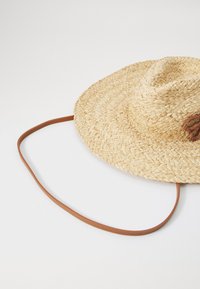 Pălărie de soare din paie, cu boruri largi, având o textură naturală împletită și o curea din piele maro pentru o utilizare sigură.