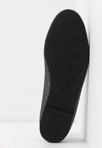 Semelle de chaussure de ballet noire mate avec une surface texturée, arborant un logo et un motif stylisé de chausson de ballet. Bords renforcés pour plus de durabilité.