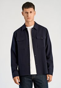 Navy blauwe overhemd met knopen, twee borstzakken, een kraag en een rechte snit. Gemaakt van een gladde, duurzame stof.