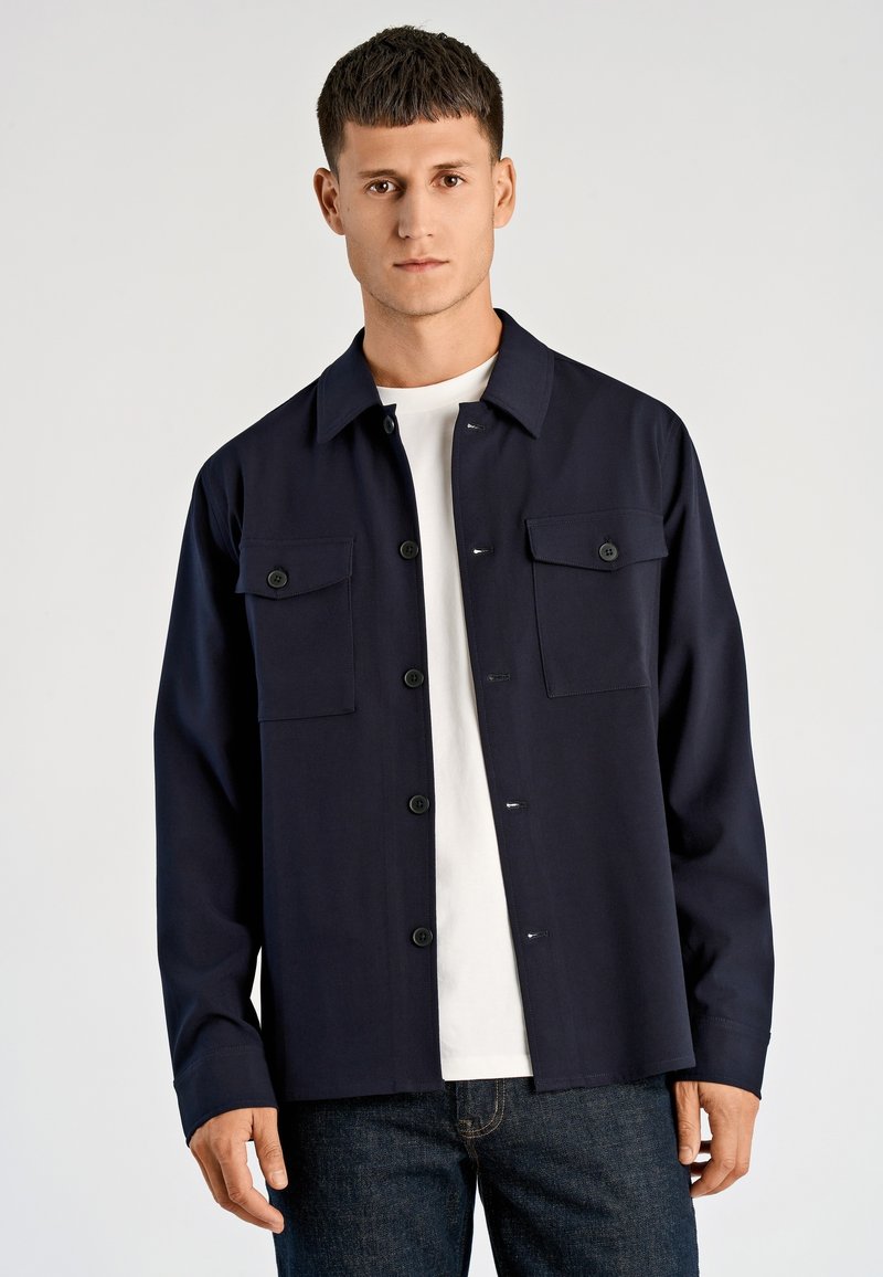 Navy blauwe overhemd met knopen, twee borstzakken, een kraag en een rechte snit. Gemaakt van een gladde, duurzame stof.