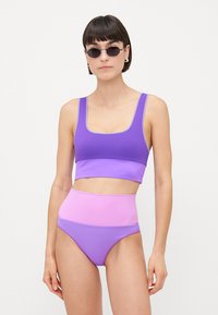 Μωβ και ροζ μπικίνι σετ που διαθέτει crop top με τετράγωνη λαιμόκοψη και φαρδιές τιράντες, καθώς και ψηλόμεσο σλιπ, κατασκευασμένα από απαλό, ελαστικό ύφασμα.