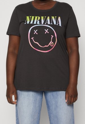 T-shirt sombre avec le texte coloré "Nirvana" et un visage souriant aux yeux barrés, porté par une personne en jean bleu clair.