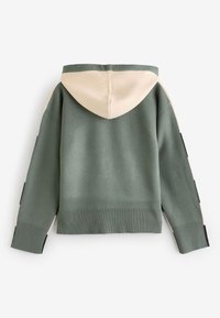 Huppari vihreänä ja beigenä, jossa on ribbireunat hihoissa ja helmassa, sekä mustat yksityiskohdat hihojen varrella. Valmistettu pehmeästä neulemateriaalista.