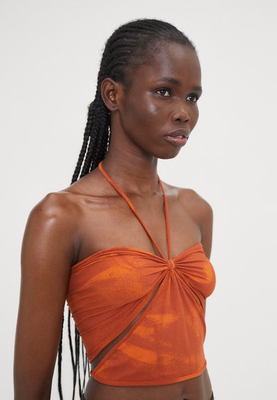 Orange halter top made of lightweight fabric, featuring a twist front design, side cutout, and textured finish with varying patterns.