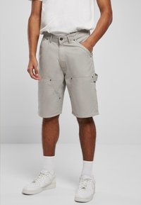 Pantaloni cargo grigi chiari con multiple tasche, vestibilità comoda e dettagli di cuciture a contrasto. Il tessuto è liscio e resistente, adatto per un abbigliamento casual.
