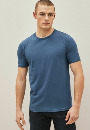 T-shirt blu in cotone a maniche corte con collo a giro, caratterizzato da una texture liscia e un design aderente. Nessun motivo o decorazione visibile.