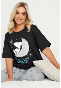 Camiseta gráfica negra de manga corta, con una luna metálica plateada y Snoopy. El texto en turquesa dice: "Nota para mí: RELÁJATE."