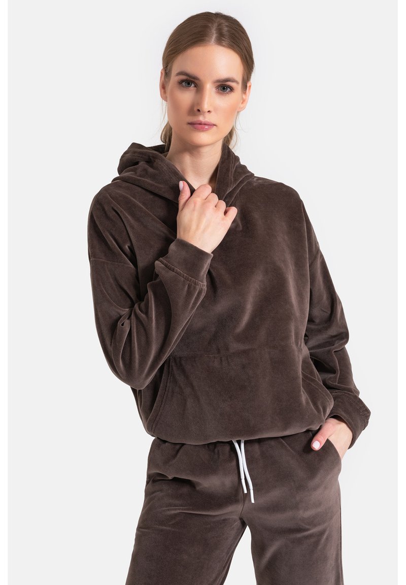 Brązowa, pluszowa bluza z kapturem, dużą kieszenią z przodu, regulowanym sznurkiem w kapturze i luźnym krojem. Długie rękawy z mankietami. W zestawie z pasującymi spodenkami.