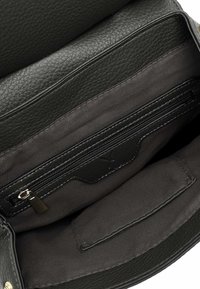 Interior de un bolso de cuero negro que cuenta con un bolsillo con cremallera, un forro de tela suave y un diseño elegante con acentos cosidos.