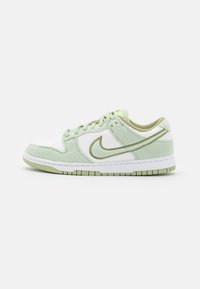 Baskets Nike avec une texture peluche blanche et vert clair, arborant un logo vert, une semelle intermédiaire blanche et une semelle extérieure en caoutchouc à motif.