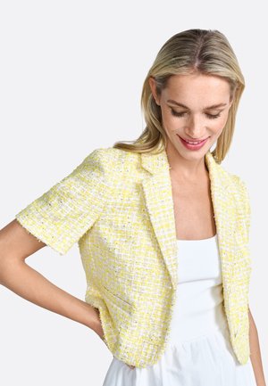 Yellow tweed blazer with short sleeves, featuring a textured weave and frayed edges. Open front design with a structured fit.